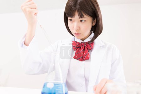 Photo for Asian female student holding pipette during chemistry lesson - Royalty Free Image