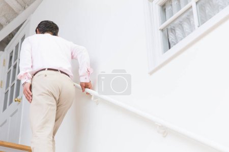 Téléchargez les photos : Senior asiatique homme en blanc chemise marche sur escaliers - en image libre de droit