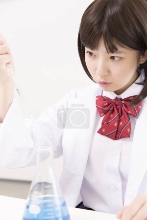 Foto de Asiático mujer estudiante holding pipeta durante química lección - Imagen libre de derechos
