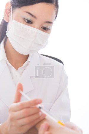 Foto de Retrato de joven hermosa japonesa médico en bata de laboratorio haciendo la inyección para el paciente en el hospital - Imagen libre de derechos