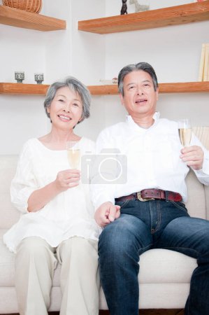 Téléchargez les photos : Senior asiatique couple boire champagne à la maison - en image libre de droit
