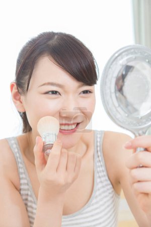 Photo for Asian young woman  with mirror applying make up - Royalty Free Image