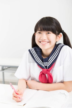 Téléchargez les photos : Souriant Japonais étudiant en uniforme scolaire étudiant à l'école - en image libre de droit