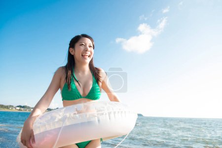 Téléchargez les photos : Jeune femme asiatique posant au bord de la mer avec anneau gonflable - en image libre de droit