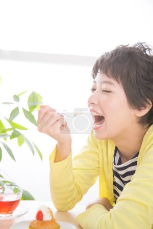 Téléchargez les photos : Portrait de jeune asiatique femme manger petit déjeuner - en image libre de droit