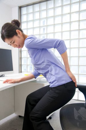 Photo for Young businesswoman suffering back pain in the office at the workplace. - Royalty Free Image