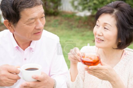 Téléchargez les photos : Heureux asiatique couple boire thé à l'extérieur - en image libre de droit