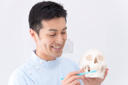 Foto de Dentista masculino en clínica dental con cráneo - Imagen libre de derechos