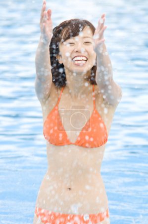 Téléchargez les photos : Jeune femme japonaise en maillot de bain coloré s'amuser à la piscine, concept de vacances - en image libre de droit