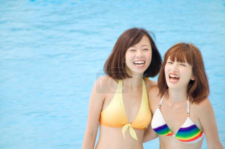 Téléchargez les photos : Belles femmes japonaises en maillots de bain colorés s'amuser à la piscine, concept de vacances - en image libre de droit