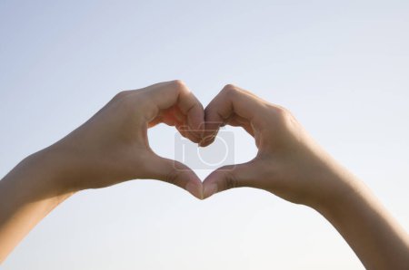 Téléchargez les photos : Mains de femme montrant la forme du cœur sur fond de ciel flou. concept d'amour - en image libre de droit