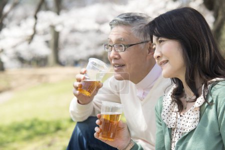 Photo for Close up asian mature couple drinking beer in park - Royalty Free Image