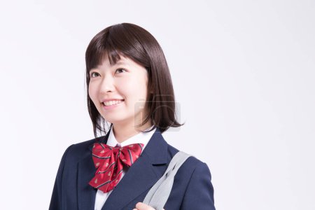 Téléchargez les photos : Portrait studio d'écolière japonaise souriante avec sac - en image libre de droit