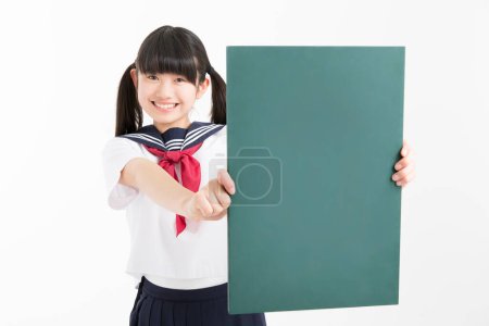 Foto de Retrato de hermosa joven estudiante en uniforme escolar sosteniendo tablero en blanco verde - Imagen libre de derechos