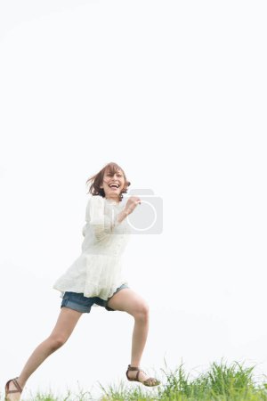 Téléchargez les photos : Femme heureuse sautant sur l'herbe dans le champ - en image libre de droit