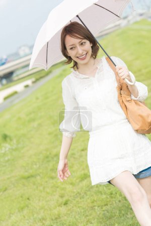 Téléchargez les photos : Belle jeune femme japonaise avec parapluie dans le parc d'été - en image libre de droit