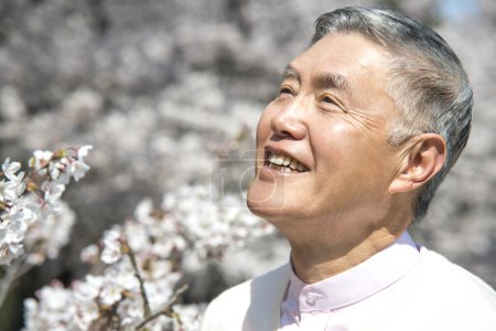 Photo for Senior asian man in the park with  blooming trees - Royalty Free Image
