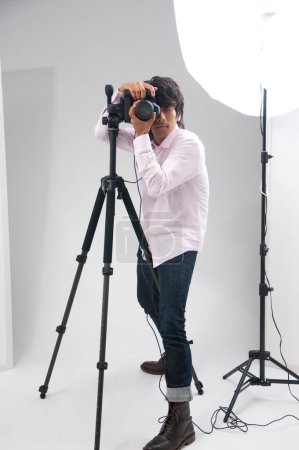 Foto de Asiático joven guapo macho fotógrafo hold DSLR cámara en manos - Imagen libre de derechos
