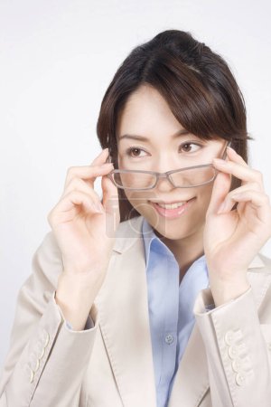 Photo for Portrait of a businesswoman putting on glasses - Royalty Free Image
