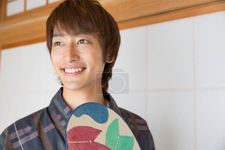 portrait of handsome japanese young man in traditional yukata in ethnic hot spring hotel