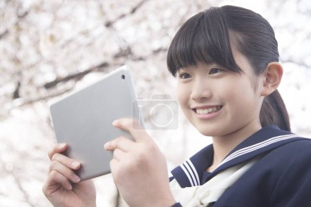 Foto de Retrato de un hermoso estudiante japonés usando tableta en la calle - Imagen libre de derechos
