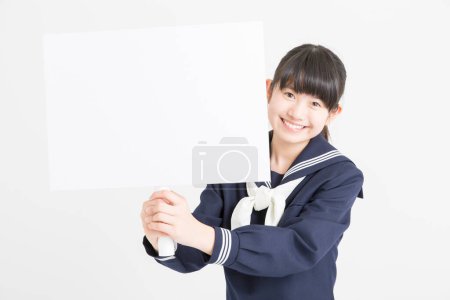 Photo for Portrait of beautiful young student in school uniform holding blank poster on white background - Royalty Free Image