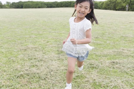 Photo for Cute Japanese girl walking in summer park, daytime portrait of funny kid having fun outdoors - Royalty Free Image
