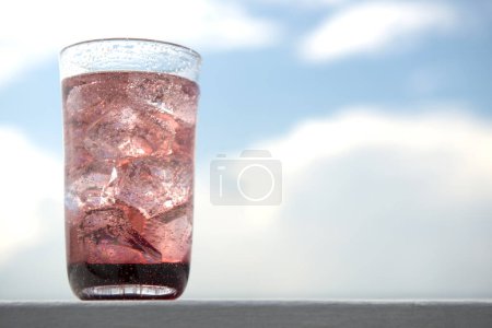 Téléchargez les photos : Un verre de soda avec de la glace sur fond bleu ciel - en image libre de droit