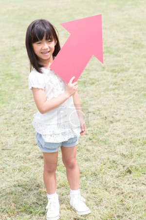 Téléchargez les photos : Petite fille avec signe de flèche à l'extérieur - en image libre de droit