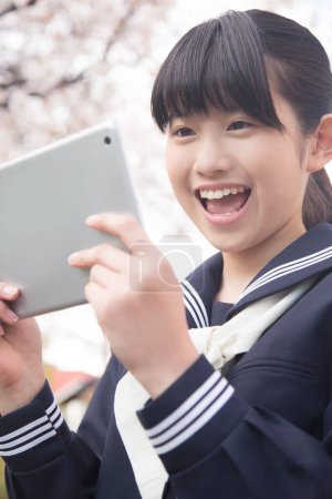 Photo for Portrait of beautiful Japanese student using tablet on street - Royalty Free Image