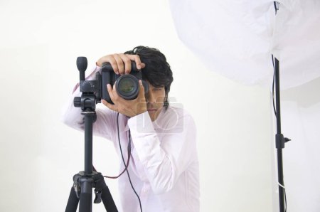 Téléchargez les photos : Asiatique jeune beau mâle photographe tenir appareil photo reflex numérique dans les mains - en image libre de droit
