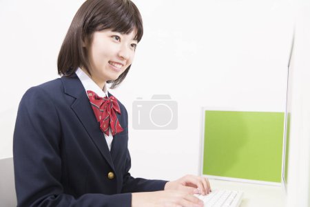 Photo for Young Japanese schoolgirl working with computer - Royalty Free Image