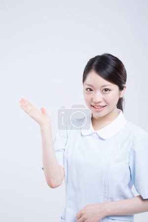 Téléchargez les photos : Portrait de belle jeune asiatique médecin en uniforme isolé sur blanc - en image libre de droit