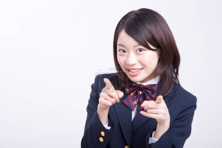 Photo for Studio portrait of smiling Japanese schoolgirl in uniform pointing - Royalty Free Image