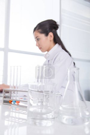 Foto de Retrato de joven hermosa japonesa científica en bata de laboratorio trabajando en laboratorio - Imagen libre de derechos