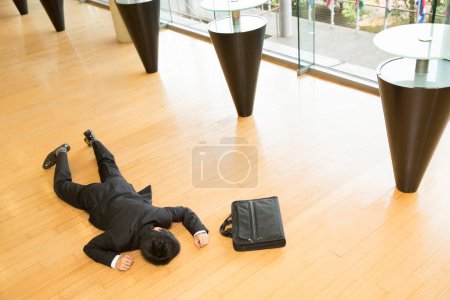 Foto de Hombre tendido en el suelo en la oficina - Imagen libre de derechos