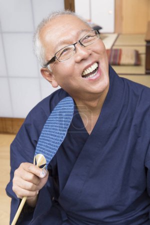 Téléchargez les photos : Portrait d'un homme asiatique senior avec ventilateur en bois - en image libre de droit