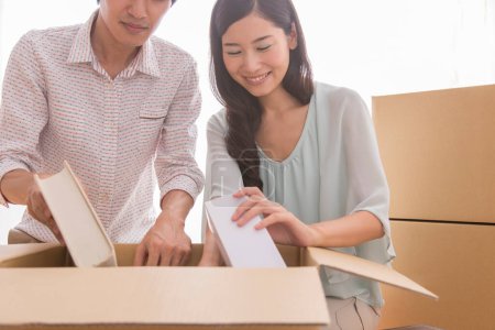 Photo for Young asian man and woman with cardboard boxes moving into new apartment - Royalty Free Image