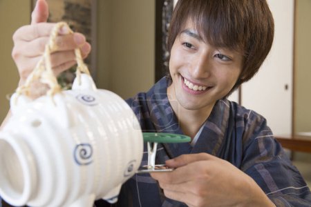 Foto de Retrato de joven japonés guapo en yukata tradicional usando repelente antimosquitos en hotel de aguas termales étnicas - Imagen libre de derechos