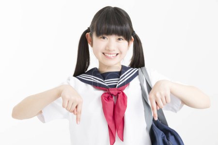 Foto de Retrato de hermosa joven estudiante en uniforme escolar apuntando sobre fondo blanco - Imagen libre de derechos