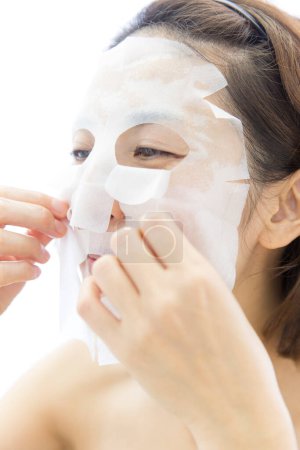Téléchargez les photos : Portrait de belle femme japonaise mature avec masque facial hydratant sur fond blanc - en image libre de droit