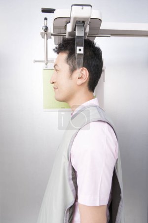 Téléchargez les photos : Asiatique l'homme est à la recherche à une machine avec un sourire, faire 3d image de mâchoires - en image libre de droit