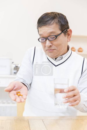 Téléchargez les photos : Asiatique senior l'homme ayant pilules à la maison - en image libre de droit