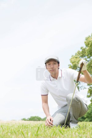 Foto de Asiático hombre en un blanco camisa y gris pantalones jugando golf - Imagen libre de derechos