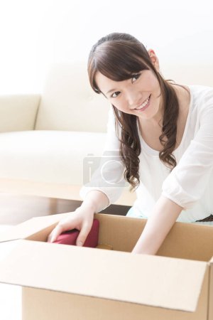 Téléchargez les photos : Asiatique femme déballage boîte à nouveau appartement - en image libre de droit