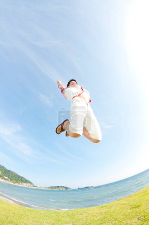 Téléchargez les photos : Jeune homme sautant contre le ciel bleu - en image libre de droit