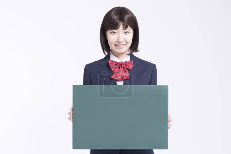 Téléchargez les photos : Jeune asiatique écolière montrant vierge vert conseil sur fond blanc - en image libre de droit