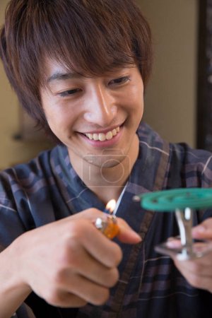 Porträt eines hübschen japanischen jungen Mannes in traditioneller Yukata mit Anti-Mückenschutzmittel in einem ethnischen Thermalhotel