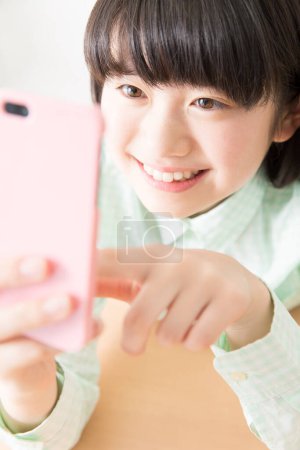 Foto de Sonriente chica japonesa usando teléfono inteligente - Imagen libre de derechos
