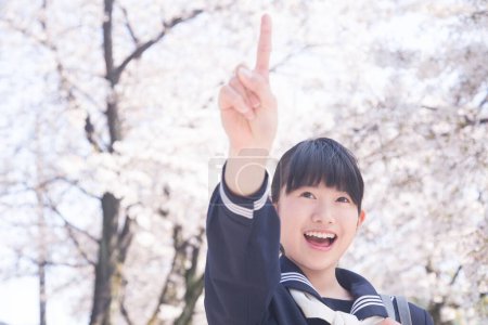 Foto de Cerrar hasta hermosa asiática escuela chica posando en parque con la floración árboles en el fondo - Imagen libre de derechos